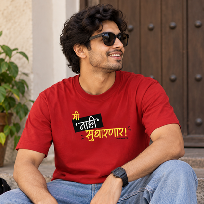 A man wearing a bright red graphic t-shirt and blue jeans sits on stone steps outdoors. The t-shirt features a bold black and yellow Marathi slogan.